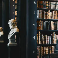 Busty filozofów w bibliotece, symbolizujące wieczny humanizm i wiedzę.