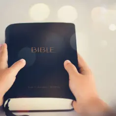 Dziecko trzyma Biblię, szukając w niej przykazania miłości.