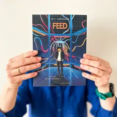 Okładka książki "Feed" M.T. Andersona. Młody człowiek w futurystycznym otoczeniu, otoczony kablami, symbolizuje dehumanizację w świecie technologii.