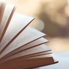 Otwarta książka, strony wirują jak wiatr, symbolizując synkretyzm w literaturze, gdzie różne wątki splatają się w jedną opowieść.