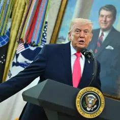 Donald Trump przemawia, stojąc przed portretem Ronalda Reagana. Człowiek istota pełna sprzeczności, w garniturze i krawacie, gestykuluje.
