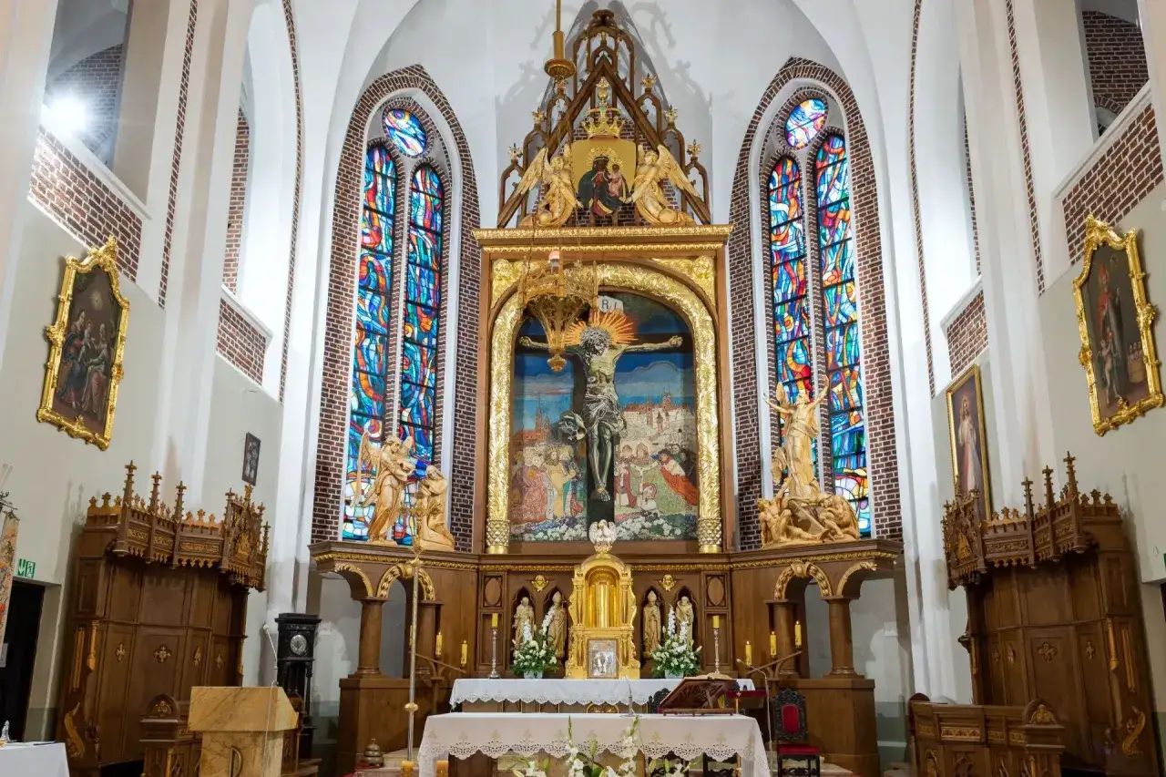 Złote tabernakulum w centrum ołtarza, otoczone witrażami i rzeźbami, stanowi serce kościoła.